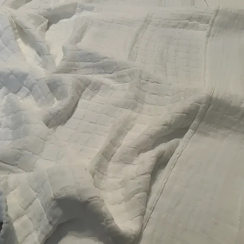 Close-up of white textured fabric with a quilted pattern