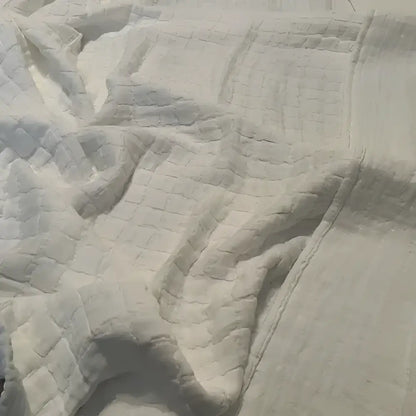Close-up of white textured fabric with a quilted pattern