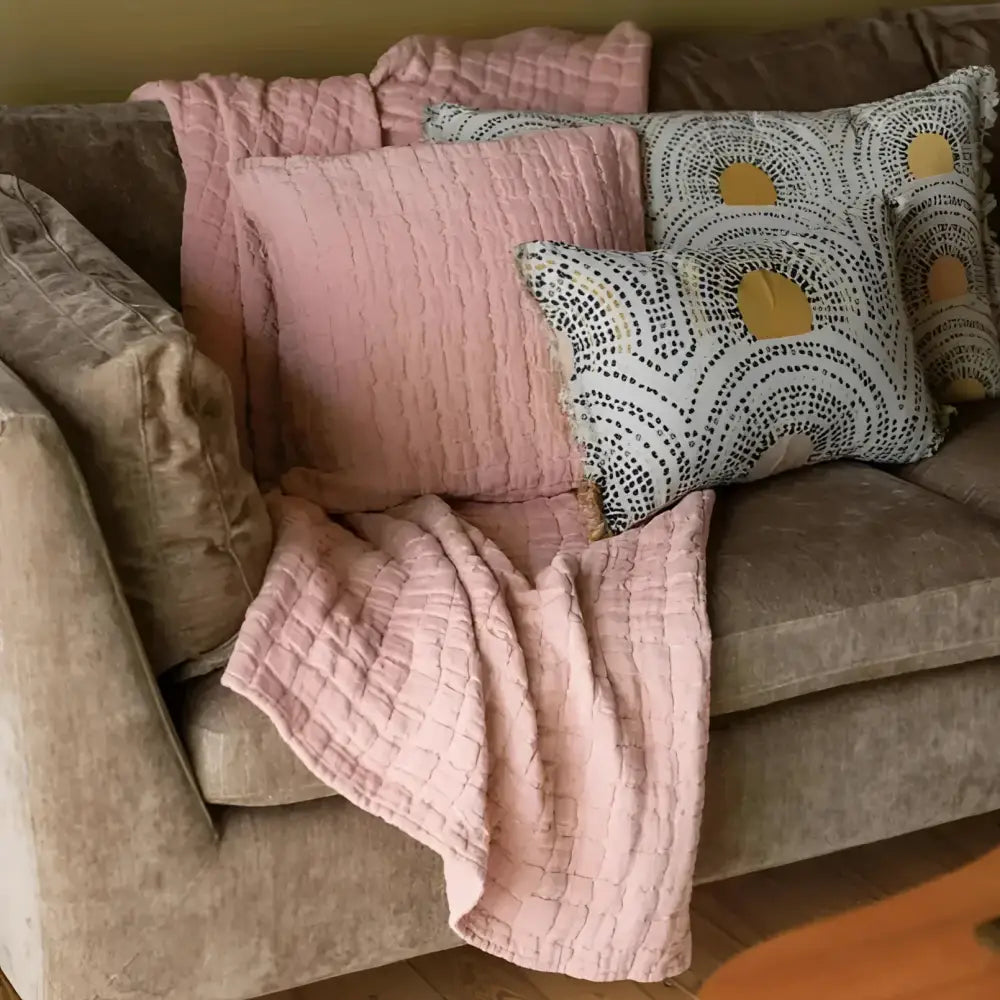 Cozy living room scene with a beige sofa adorned with clay textured pillows and a blanket.