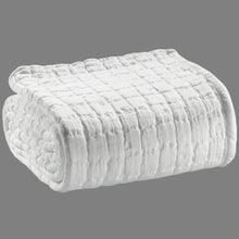 Folded textured white blanket on a gray background