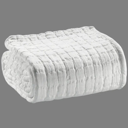 Folded textured white blanket on a gray background