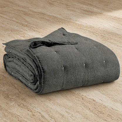 A dark gray stonewashed bed runner with soft quilted texture and subtle button detailing for queen or king beds