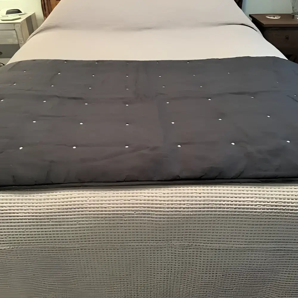 Gray bed runner on a bed with a blurred background