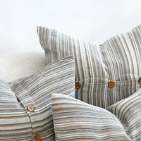 A collection of striped pillows in blues, greens, and natural colors.