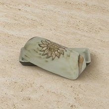 A light green handmade butter dish with a gold-toned sunflower design perfect as a sunflower butter dish