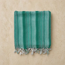 Folded teal turkish cotton hand towel with light green stripes and fringed edges handwoven by turkish artisans