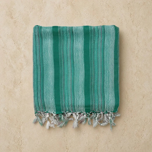 Folded teal turkish cotton hand towel with light green stripes and fringed edges handwoven by turkish artisans