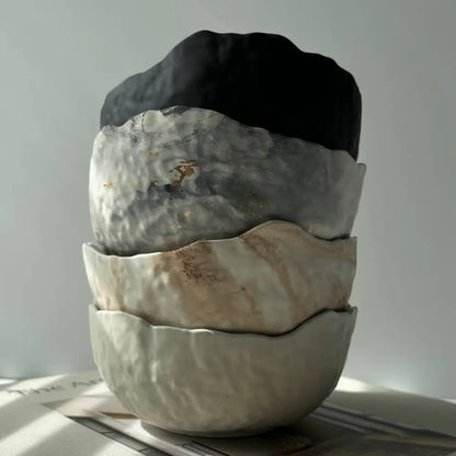 Stack of four textured raw edge concrete bowls with unique earthy tones and uneven edges