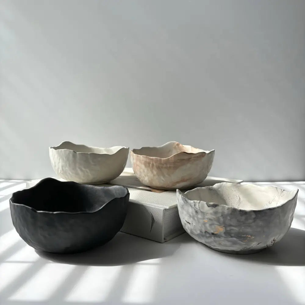 Four earthy textured raw edge concrete bowls with deliberately uneven edges for a rustic look