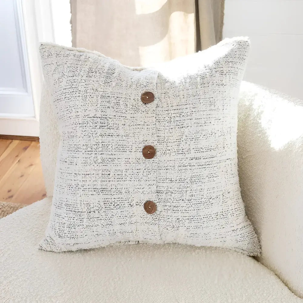 Off white and gray textured hand woven 20 inch x 20 inch pillow cover with three brown coconut buttons on one side 