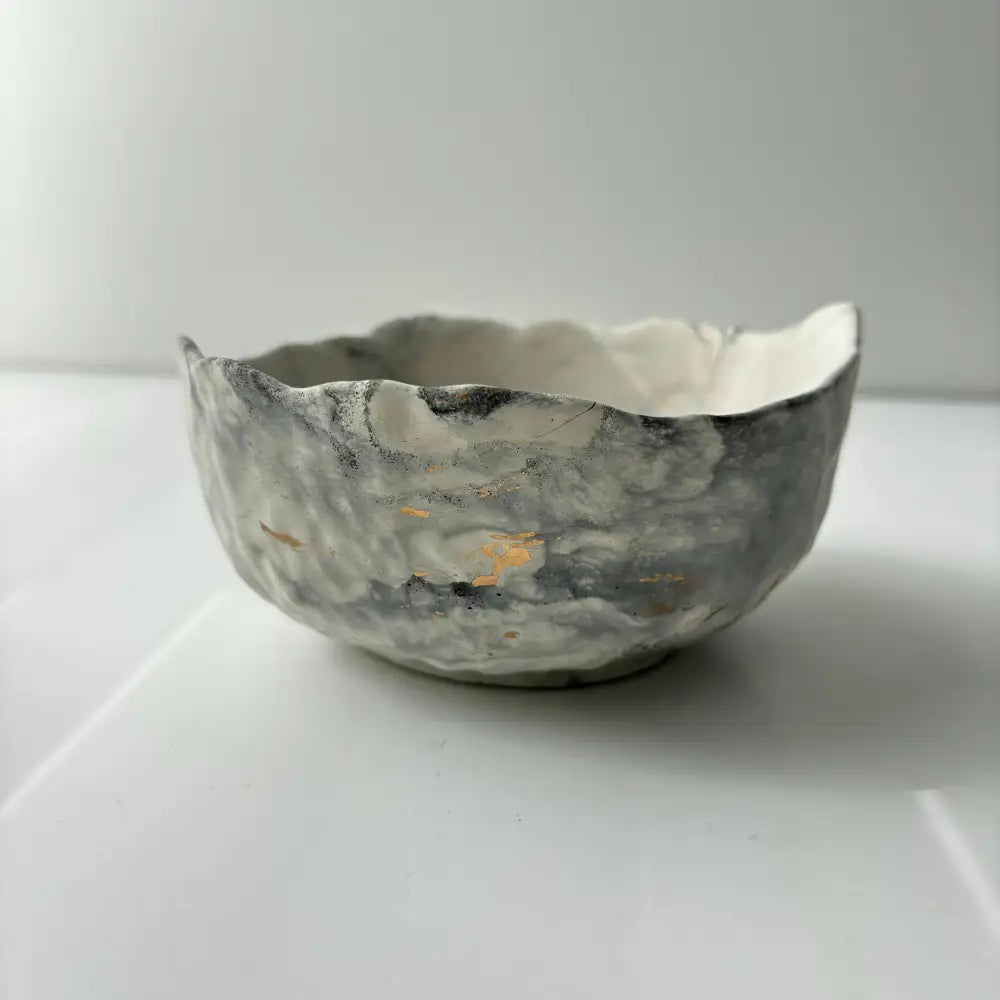 A hand poured, textured concrete bowl with intentionally irregular edges.