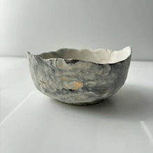 A hand poured, textured concrete bowl with intentionally irregular edges.