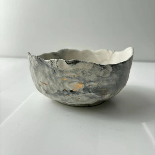 A hand poured, textured concrete bowl with intentionally irregular edges.
