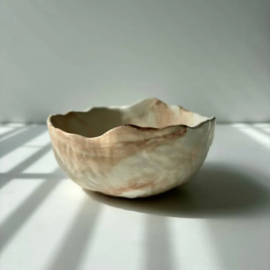 A hand poured, textured concrete bowl with intentionally irregular edges.