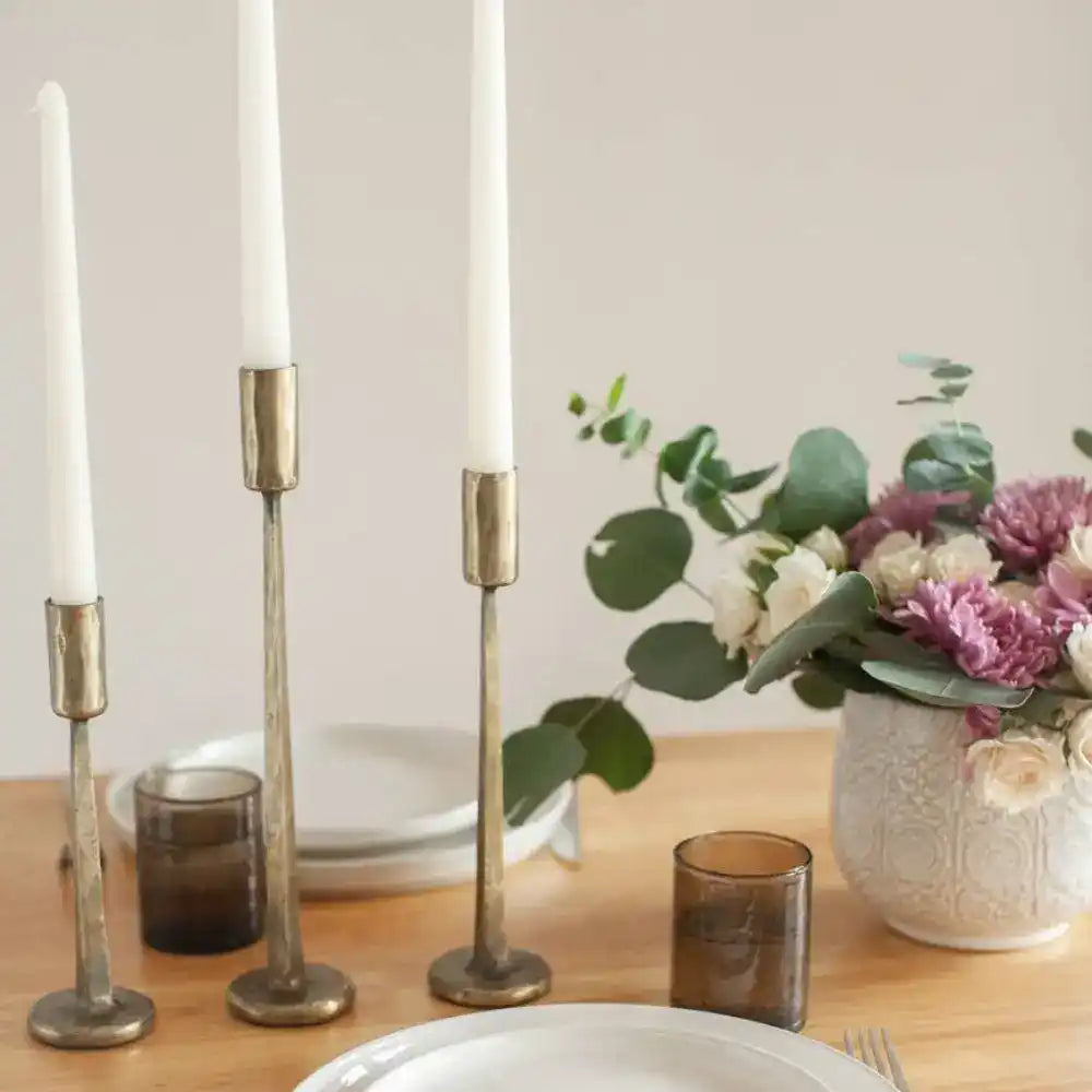 Dante Hand Forged Iron Candle Stands in brass on a wooden table with setting