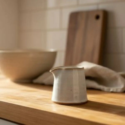 Tiny handmade ceramic condiment pitcher in off-white with rustic finish and subtle vertical ridges