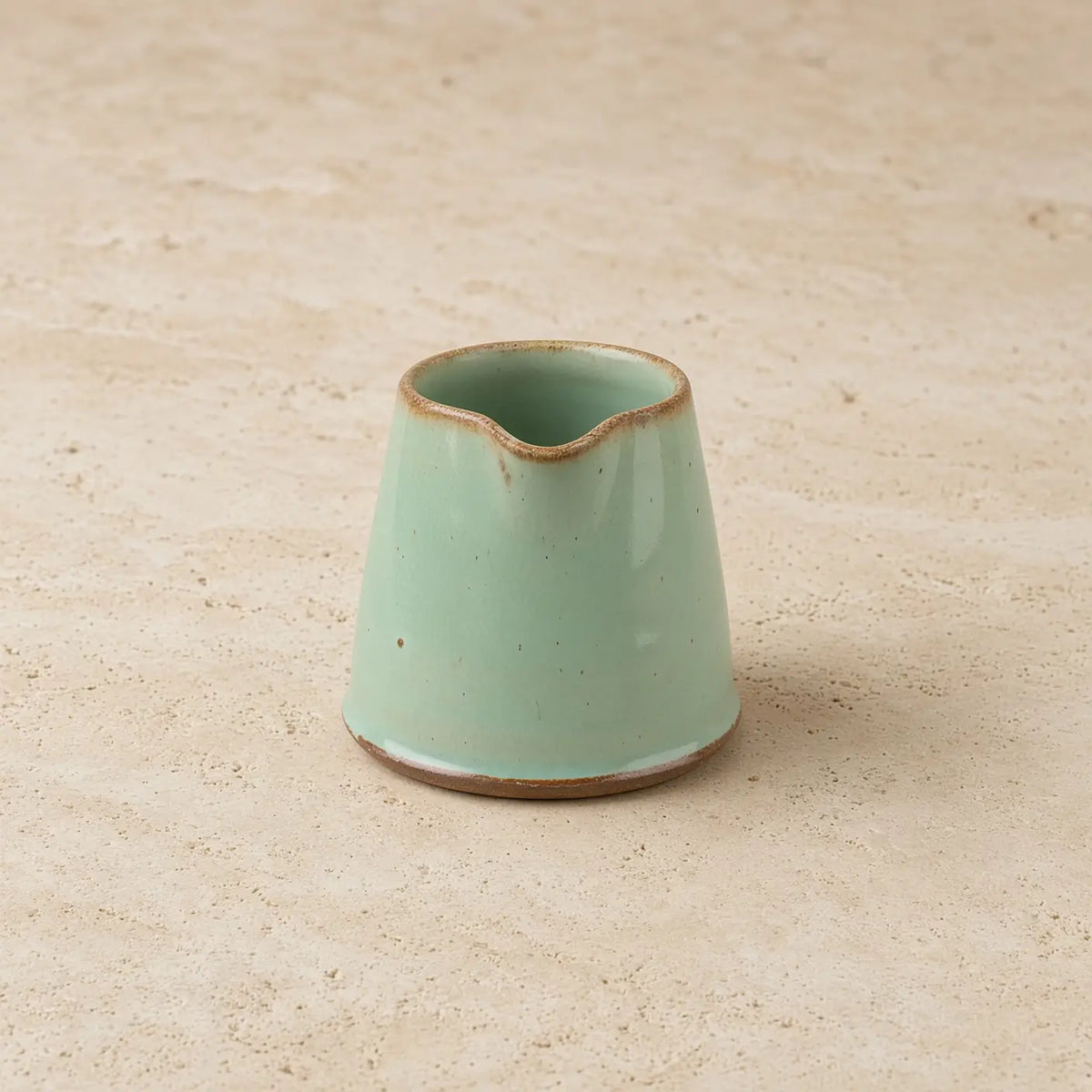 Tiny handmade ceramic condiment pitcher in matte mint green with rustic brown rim and base perfect for sauces