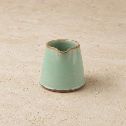 Tiny handmade ceramic condiment pitcher in matte mint green with rustic brown rim and base perfect for sauces