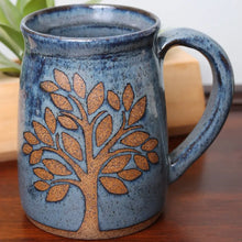 Speckled stoneware mug in blue and with a brown tree design.