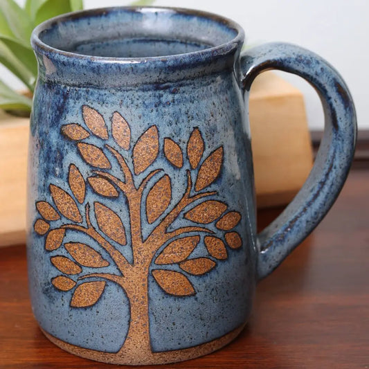 Speckled stoneware mug in blue and with a brown tree design.