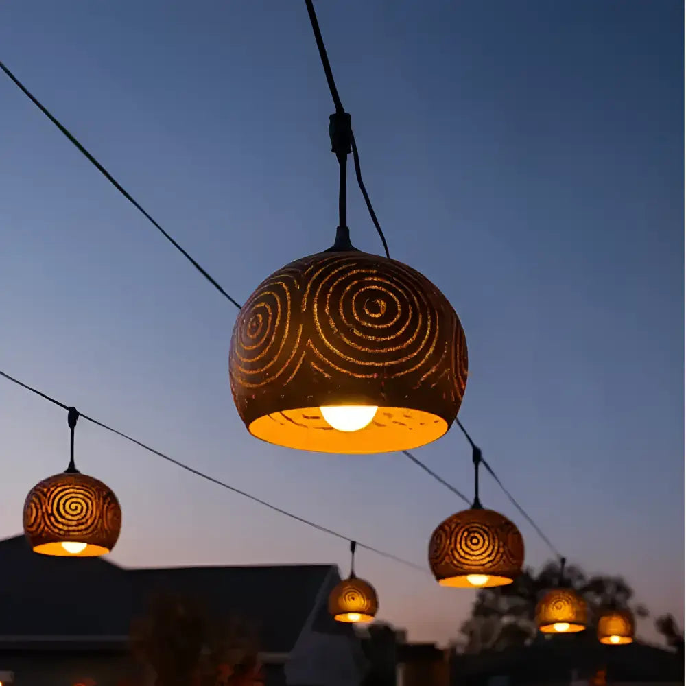 Warm-toned hand-carved coconut shades with intricate spiral patterns in a tropical coconut patio string light set