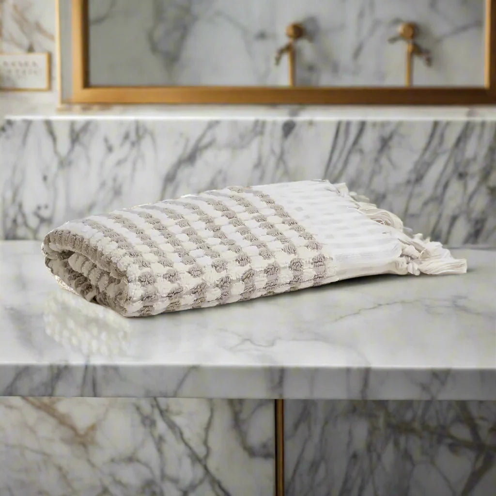 Neatly folded Turkish cotton dotted terry hand towel with tassels in white and grey