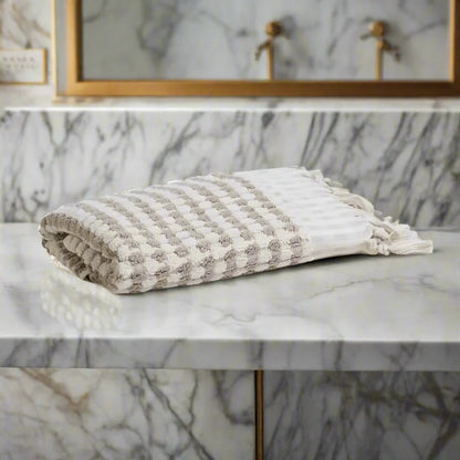 Neatly folded Turkish cotton dotted terry hand towel with tassels in white and grey