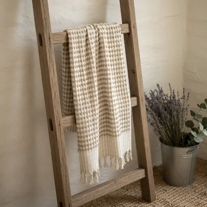Beige and cream turkish cotton dotted terry long hand towel with tassels hanging on wooden ladder