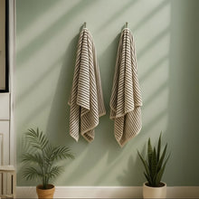 Two Melika Turkish cotton striped towels on pale green wall
