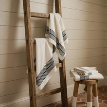 White turkish cotton bath towels with black horizontal stripes hang on a wooden ladder showing striped turkish cotton design
