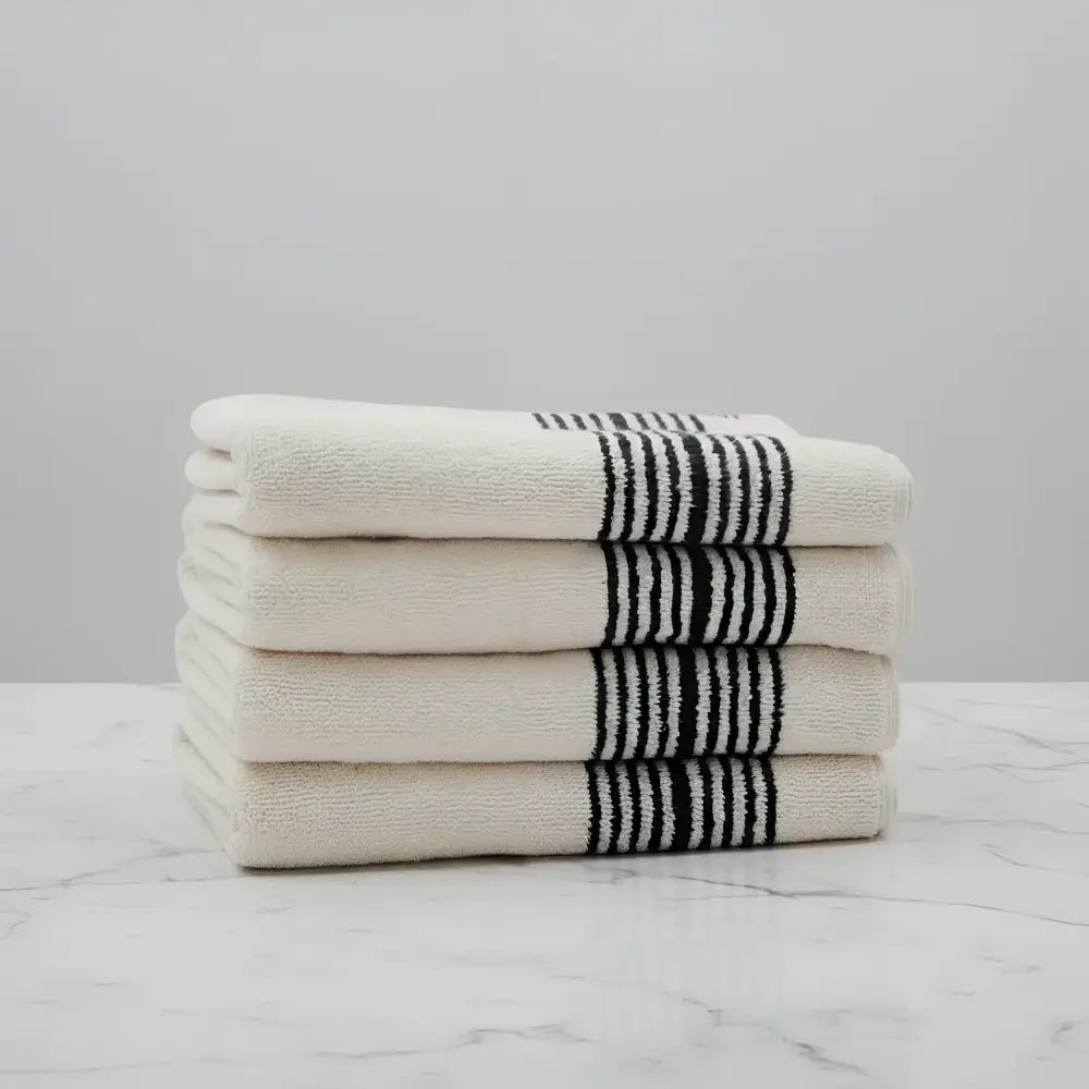 Stack of cream Turkish cotton striped towels with black edge stripes