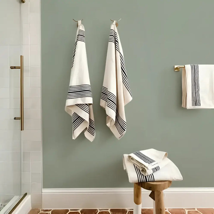 Neatly hung Turkish cotton striped bath towels on green wall