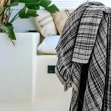 Plaid blanket draped over a white surface with a blurred background