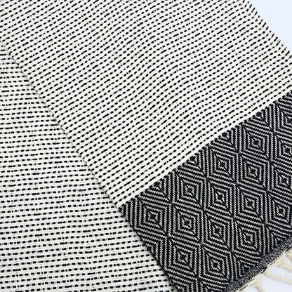 A turkish hand towel with diamonds and dots woven in black.