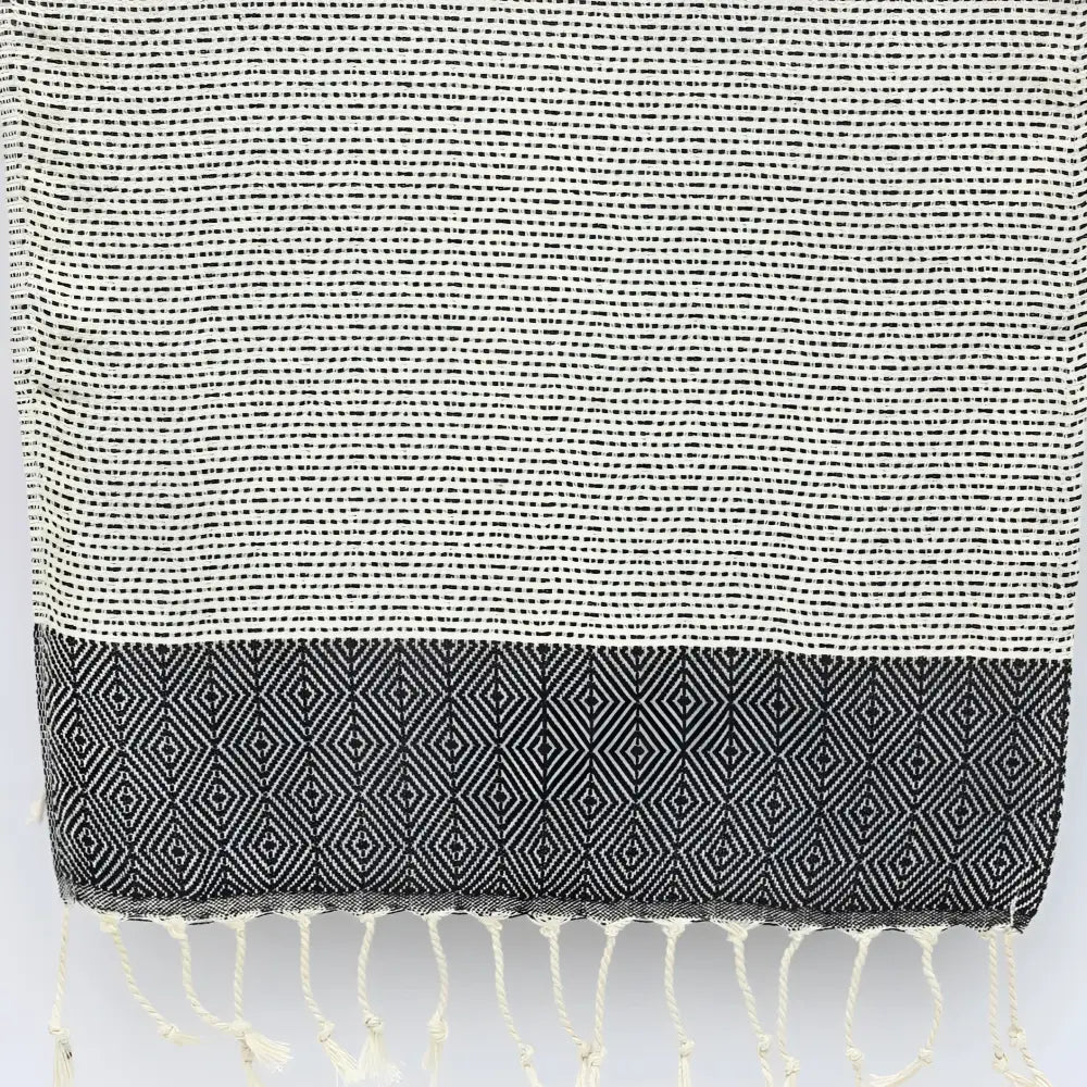 A turkish hand towel with diamonds and dots woven in black.