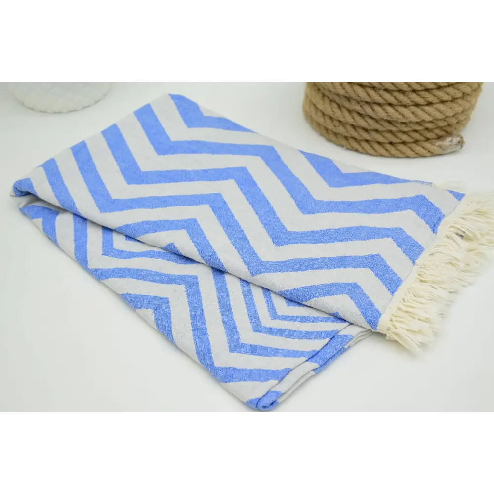 Folded turkish towel with zigzag design pale sax blue pattern and cream fringe perfect for beach or bath use