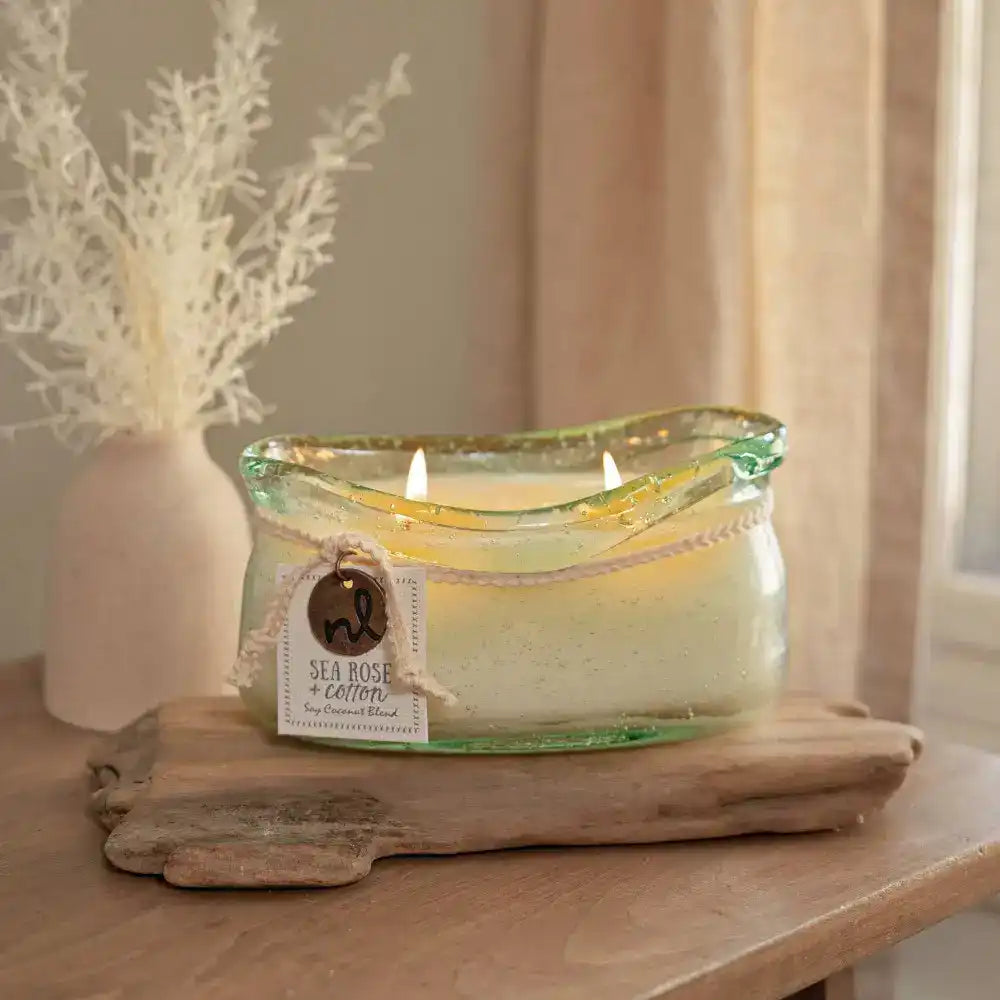 A hand-blown glass vessel with an artisan-rolled rim filled with natural candle wax with two wicks. 