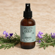 A brown glass gold room spray with black nozzle and light green label featuring wildflowers rose geranium by misc
