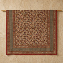 Beige and rust-red block printed vines large tablecloth with floral motifs and geometric borders hanging on wooden rod