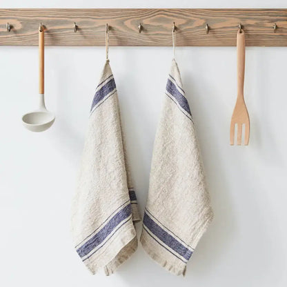 Vintage linen kitchen towel with dark blue stripes hanging from wooden rack