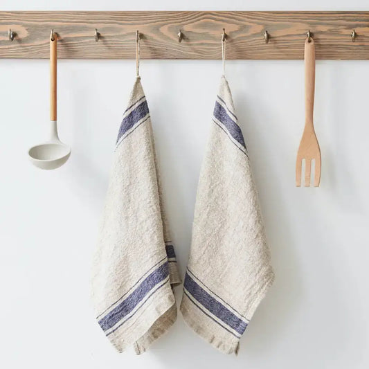 Vintage linen kitchen towel with dark blue stripes hanging from wooden rack