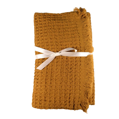 Folded mustard yellow waffle bath towel with fringed edges made of pure Aegean cotton