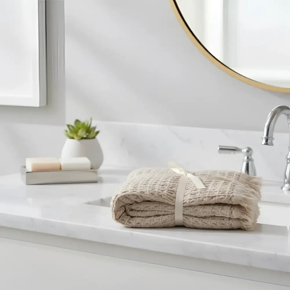 Beige waffle soft turkish hand towel made of pure aegean cotton with frayed edges and a cream ribbon tied around it
