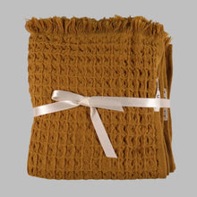 Folded mustard yellow waffle soft Turkish cotton hand towel with fringed edges and ribbon