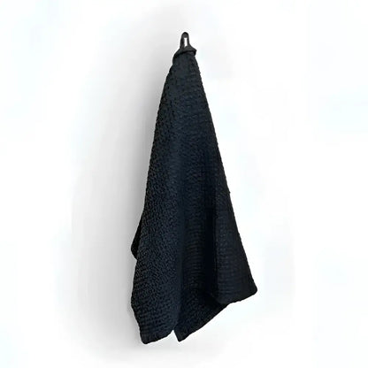Black linen-cotton blend waffle kitchen towel hanging on hook, specialized waffle weave