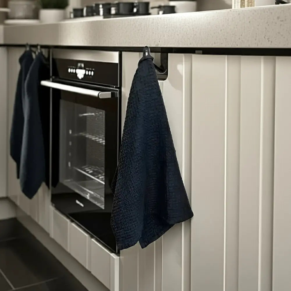 Modern black built-in oven with linen-cotton blend waffle kitchen towel hanging nearby