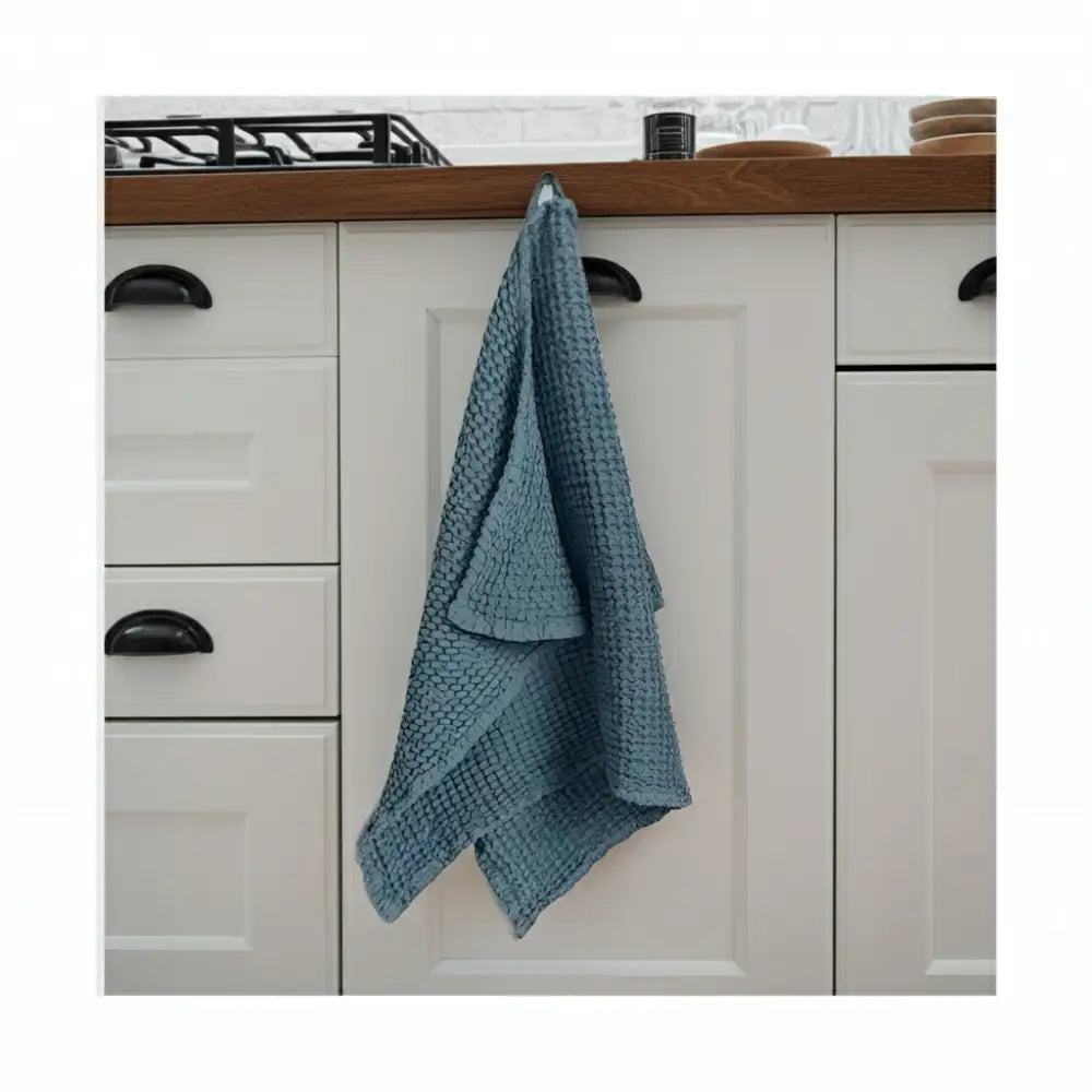 Blue linen-cotton blend waffle kitchen towel hanging on cabinet door