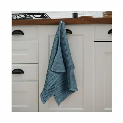 Blue linen-cotton blend waffle kitchen towel hanging on cabinet door