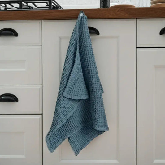 Blue linen-cotton blend waffle kitchen towel hanging on cabinet door