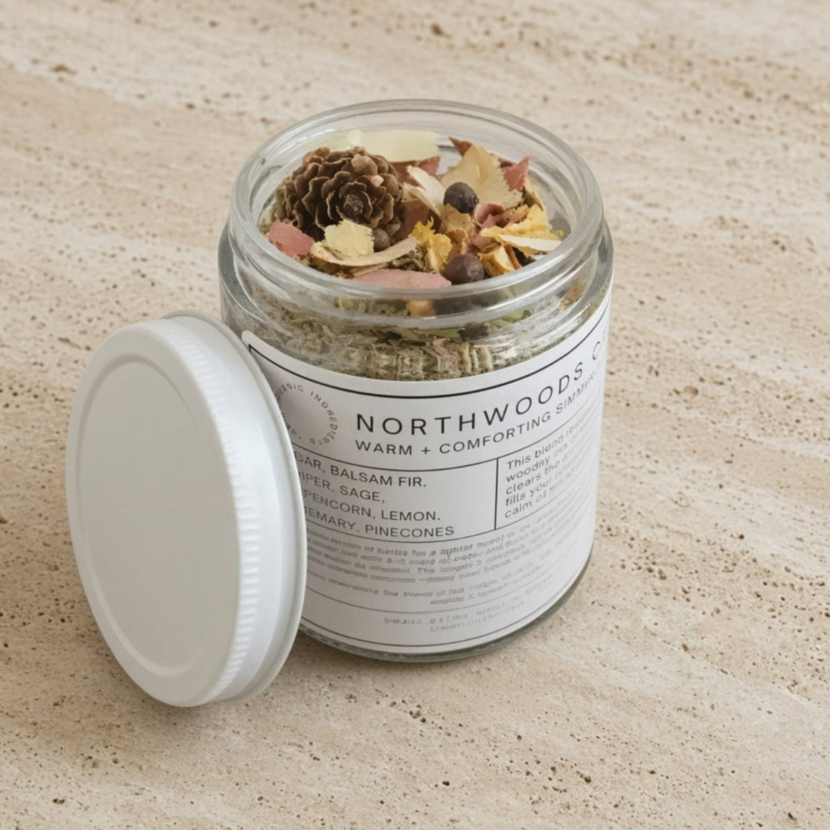 Clear glass jar with white lid labeled northwoods co comforting simmer pot blend with balsam fir scent